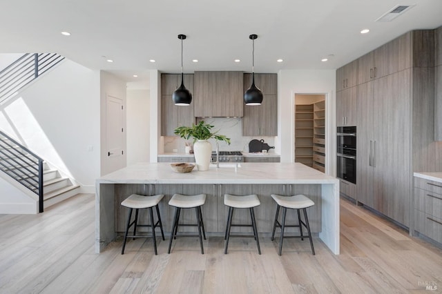 kitchen with pendant lighting, light hardwood / wood-style floors, and a large island