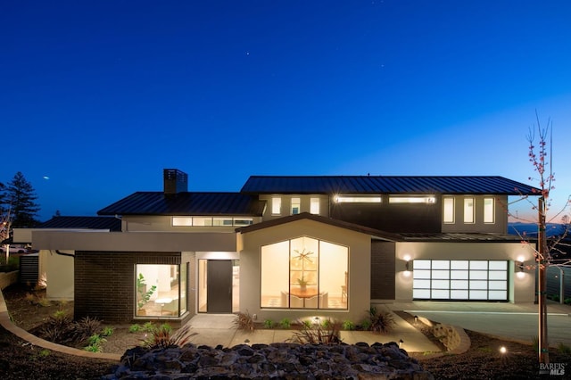 back house at dusk featuring a garage