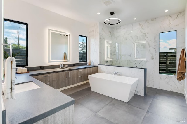 bathroom with tile walls, vanity, a tub, and concrete flooring