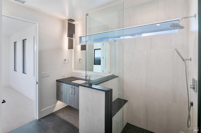 bathroom featuring a tile shower, vanity, and tile patterned floors