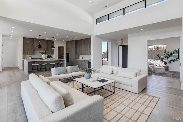 living room featuring light wood-type flooring and a towering ceiling