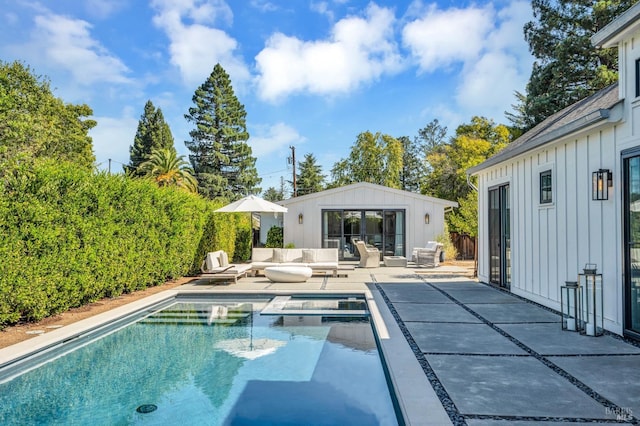 view of swimming pool featuring a patio, an in ground hot tub, and an outbuilding