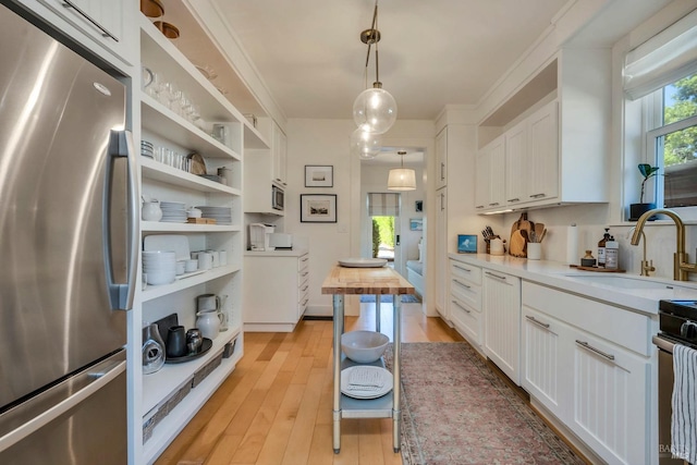 kitchen with white cabinetry, butcher block counters, stainless steel appliances, light wood-type flooring, and decorative light fixtures