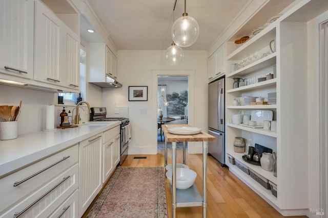 kitchen featuring pendant lighting, stainless steel appliances, and white cabinetry