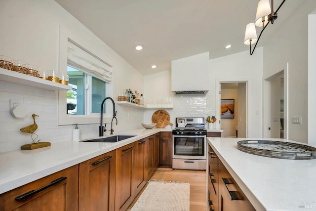 kitchen with sink, tasteful backsplash, light hardwood / wood-style flooring, stainless steel range, and vaulted ceiling