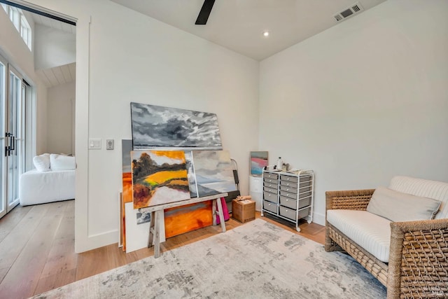 sitting room featuring ceiling fan, lofted ceiling, and light wood-type flooring