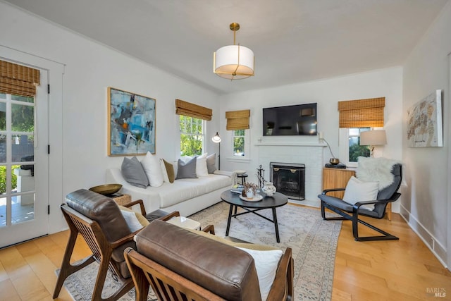 living room featuring a brick fireplace and light wood-type flooring