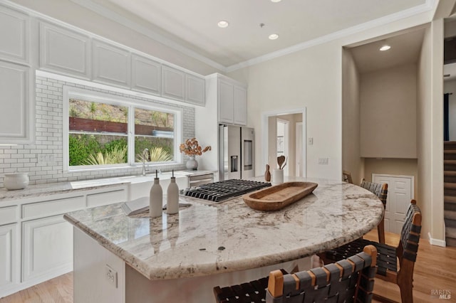 kitchen with decorative backsplash, a kitchen island, appliances with stainless steel finishes, and light stone countertops