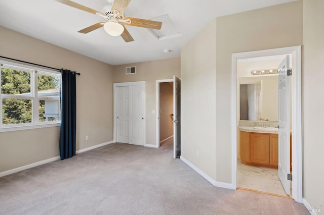 unfurnished bedroom featuring ceiling fan, light colored carpet, a closet, and ensuite bathroom