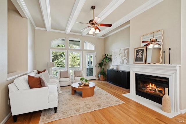 living room with ceiling fan, hardwood / wood-style flooring, crown molding, and beam ceiling