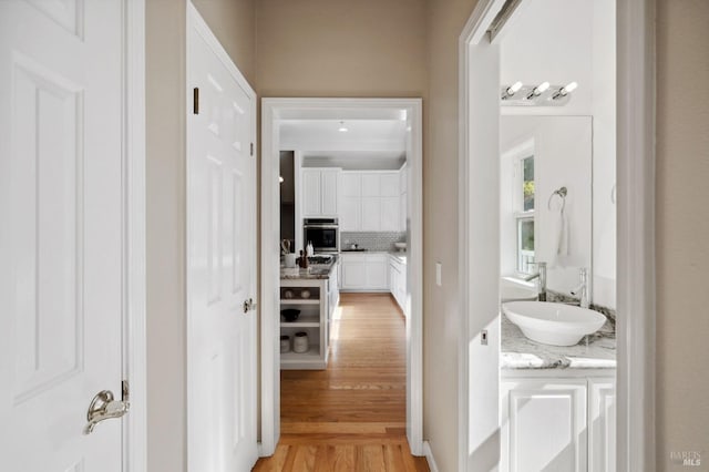 hall with light hardwood / wood-style floors and sink