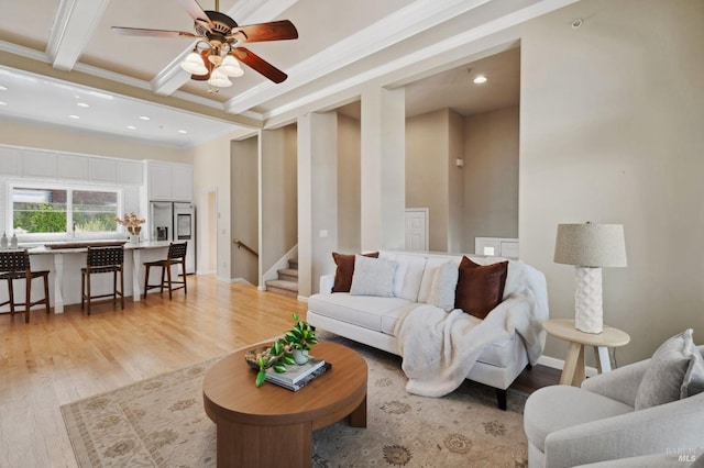 living room featuring light hardwood / wood-style flooring, beam ceiling, ceiling fan, and ornamental molding