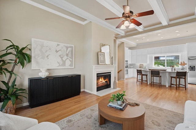 living room featuring ceiling fan, radiator, beam ceiling, ornamental molding, and light wood-type flooring