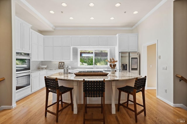 kitchen featuring stainless steel appliances, white cabinets, a center island with sink, and crown molding