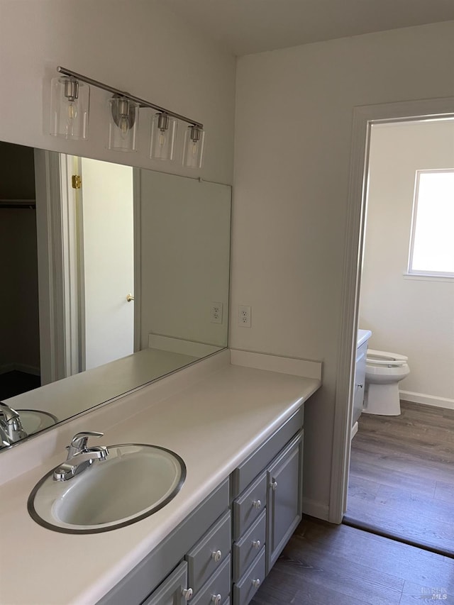 bathroom with toilet, baseboards, wood finished floors, and vanity