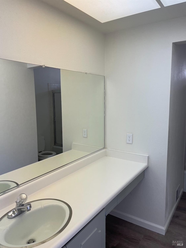 bathroom with baseboards, wood finished floors, visible vents, and vanity