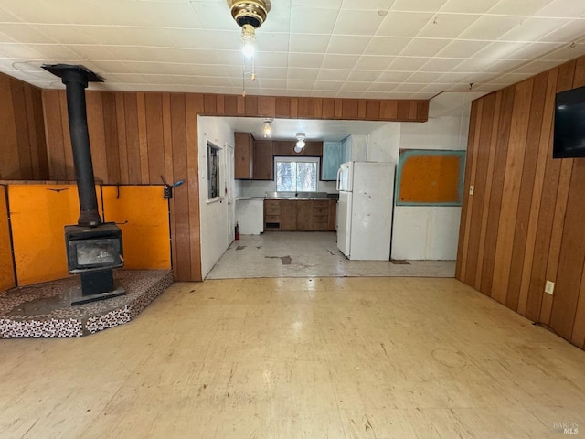 unfurnished living room with a wood stove and wooden walls