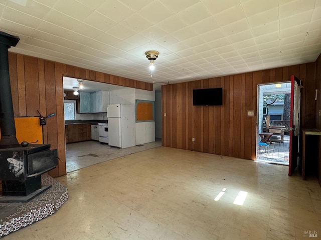 living area featuring a wood stove, wood walls, and light floors