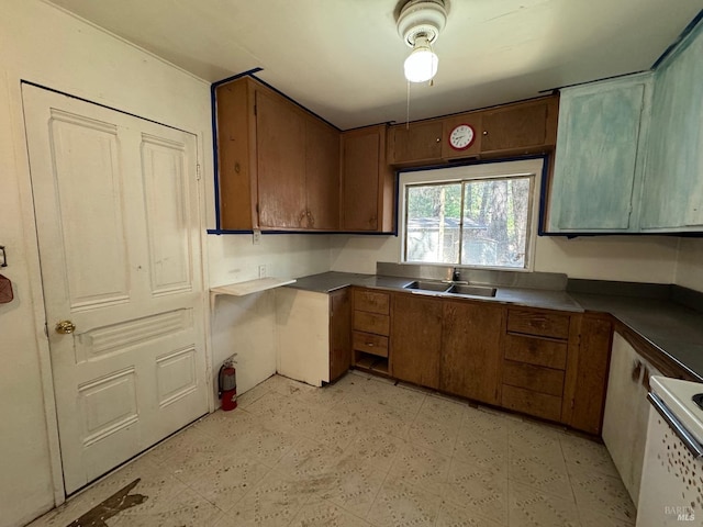 kitchen featuring light floors, stove, a sink, and brown cabinetry