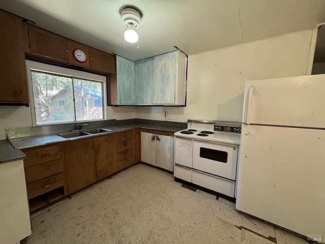 kitchen with light floors, white appliances, dark countertops, and a sink