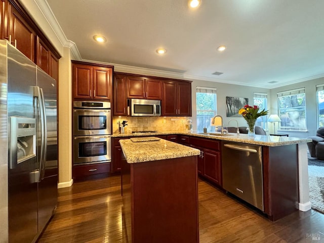 kitchen with sink, crown molding, dark hardwood / wood-style floors, a kitchen island, and stainless steel appliances