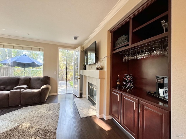 living room with a tile fireplace, crown molding, and hardwood / wood-style flooring