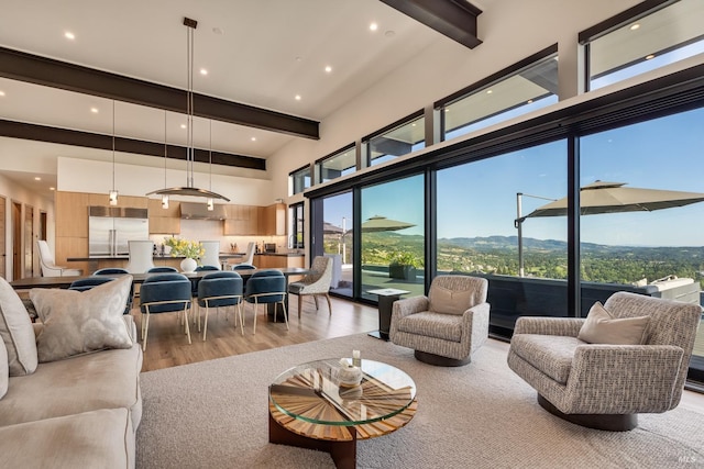 living room with a high ceiling, recessed lighting, beamed ceiling, and light wood-type flooring