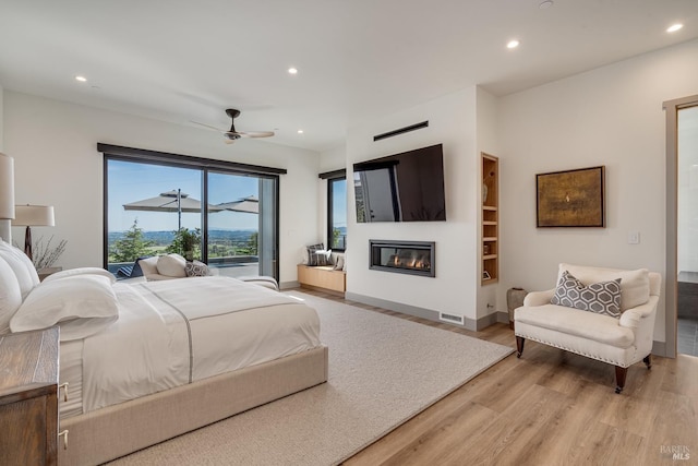 bedroom with visible vents, recessed lighting, a ceiling fan, light wood-style floors, and a glass covered fireplace