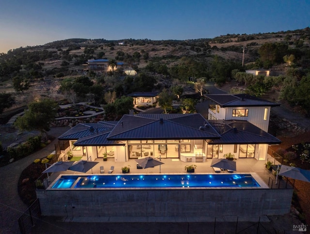 pool at dusk with fence, a patio, and a fenced in pool