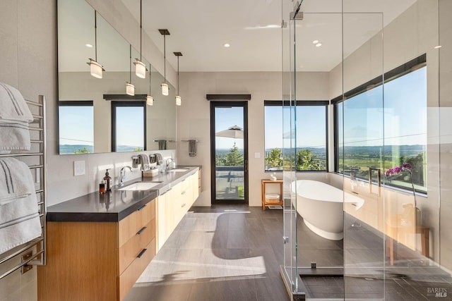 full bath with a soaking tub, double vanity, and a sink