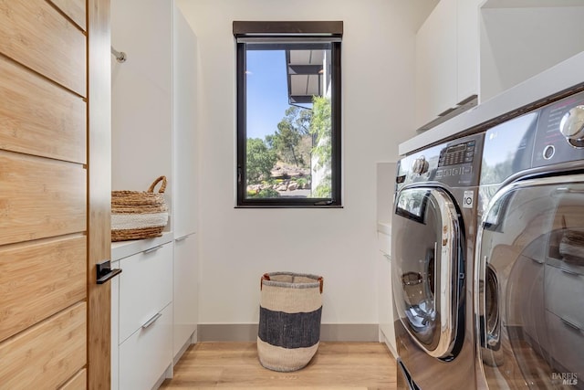 washroom with baseboards, cabinet space, separate washer and dryer, and light wood-type flooring