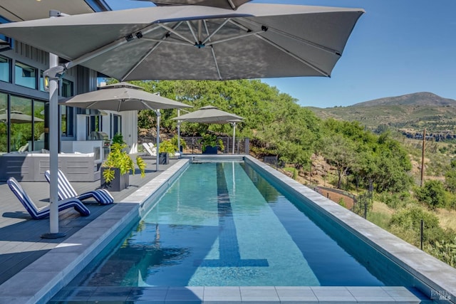 outdoor pool with a mountain view and a patio area