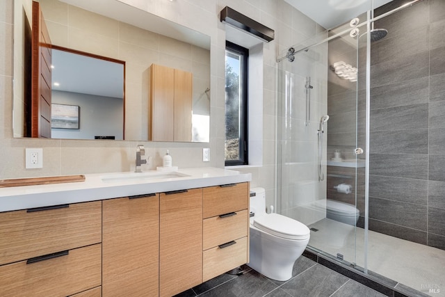 bathroom featuring tile walls, toilet, a stall shower, and vanity