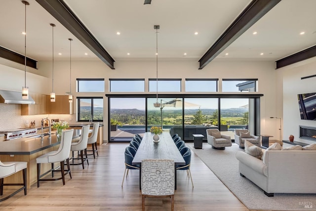 living area featuring a wealth of natural light, a high ceiling, beamed ceiling, and light wood finished floors