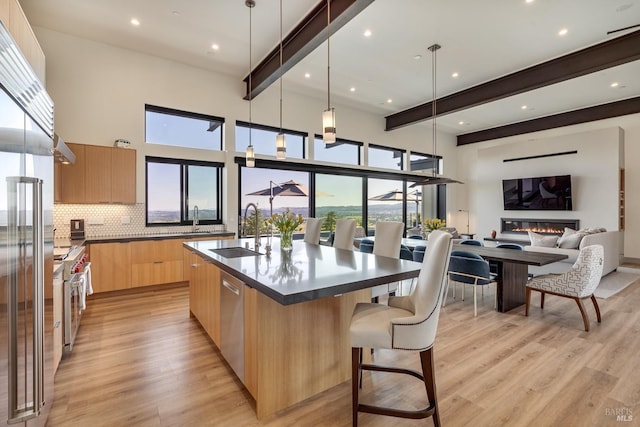kitchen with modern cabinets, a sink, dark countertops, and light brown cabinetry