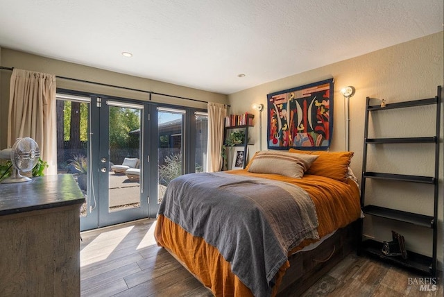 bedroom featuring access to exterior, a textured ceiling, a textured wall, and dark wood-style flooring