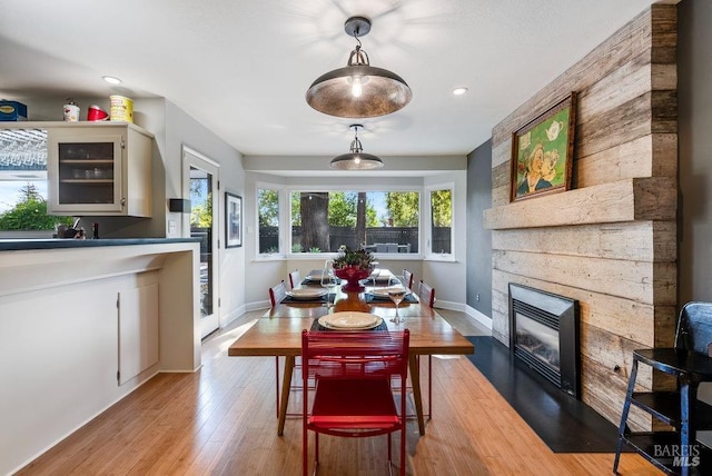 dining space featuring recessed lighting, a fireplace, light wood-type flooring, and baseboards