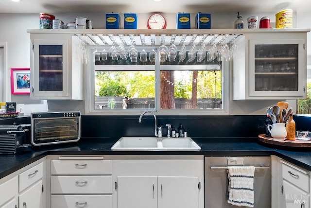 kitchen featuring a toaster, dishwasher, white cabinetry, and a sink