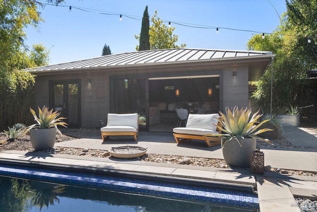 exterior space featuring an outdoor pool, metal roof, and a standing seam roof