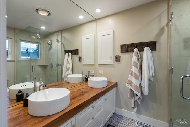 bathroom with double vanity, a stall shower, and a sink