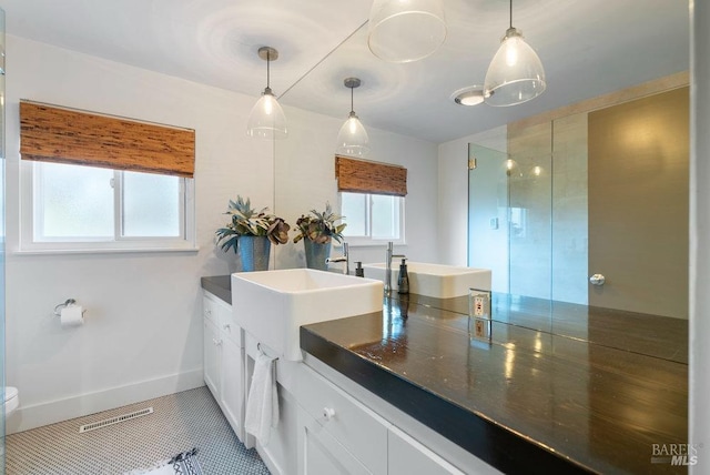 full bath with double vanity, visible vents, a stall shower, and a sink