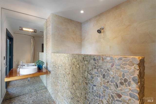 bathroom with a tile shower and a sink