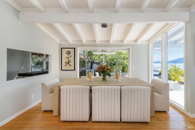 dining area with light hardwood / wood-style flooring, a mountain view, lofted ceiling with beams, and a healthy amount of sunlight