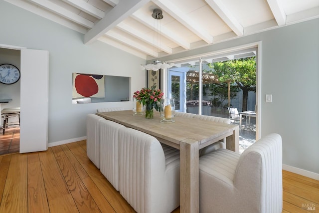 dining room featuring light wood-type flooring and lofted ceiling with beams