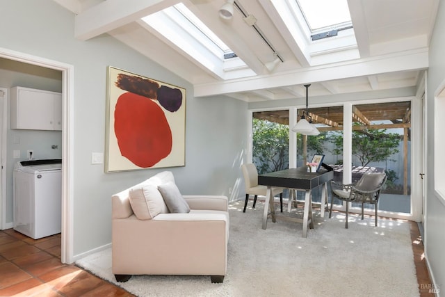 interior space featuring rail lighting, vaulted ceiling with skylight, and washer / dryer