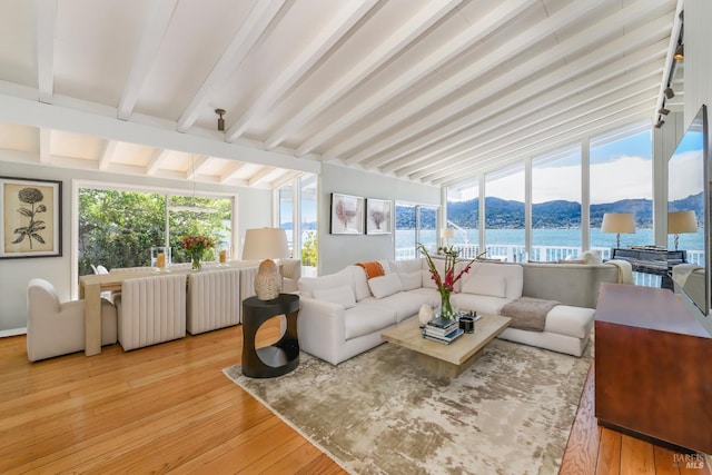 sunroom / solarium featuring vaulted ceiling with beams and a water and mountain view