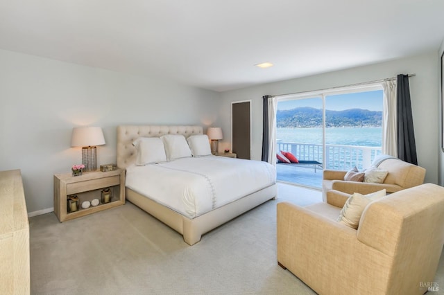 bedroom with access to outside, light colored carpet, and a water view