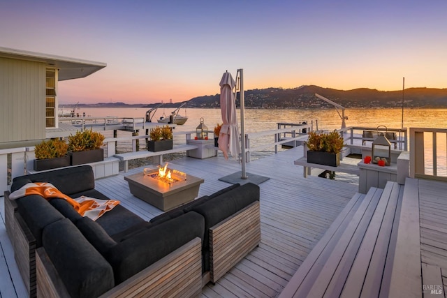 deck at dusk featuring a water and mountain view and an outdoor fire pit