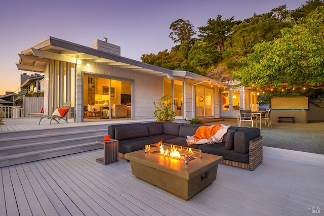 deck at dusk with an outdoor living space with a fire pit