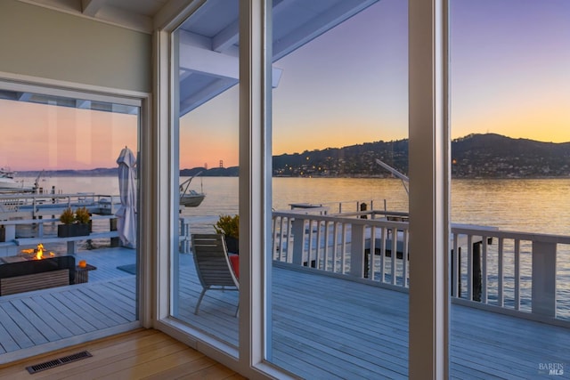 doorway to outside with light wood-type flooring, a water view, and plenty of natural light